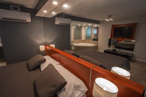 Une chambre d’hôtel moderne dotée d’un grand lit, d’une salle de bain séparée avec baignoire, d’une télévision à écran plat et d’un grand miroir.