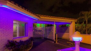 A building with a gated entrance, a covered patio area, and a small illuminated structure. - Gables Cove Hotel (Coral Gables)