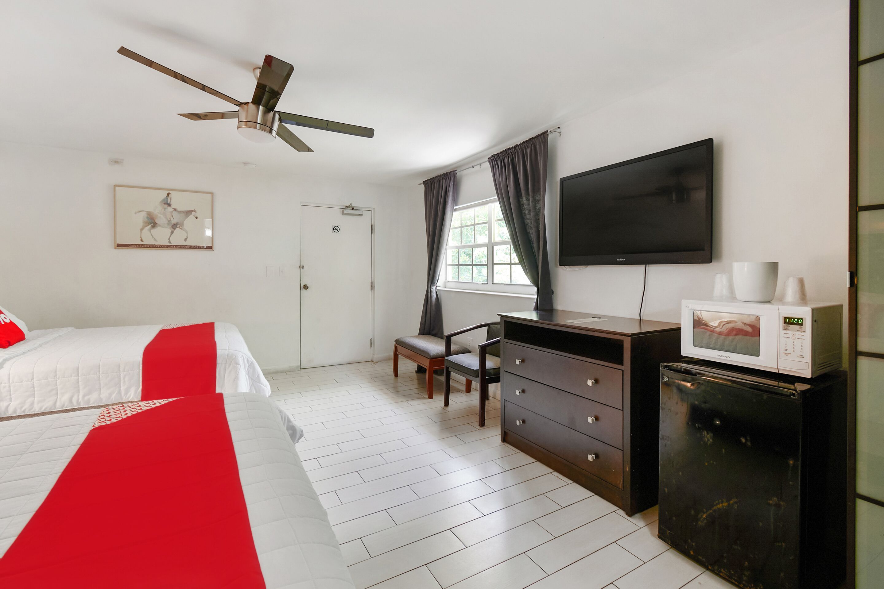 Een hotelkamer met een bed, een bureau, een stoel, een televisie, een magnetron en een koelkast.
