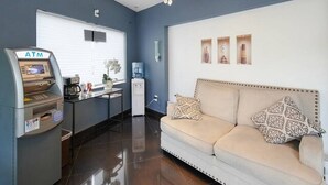 A hotel lobby with an ATM, a sofa, a water dispenser, and a chandelier. - Gables Cove Hotel (Coral Gables)