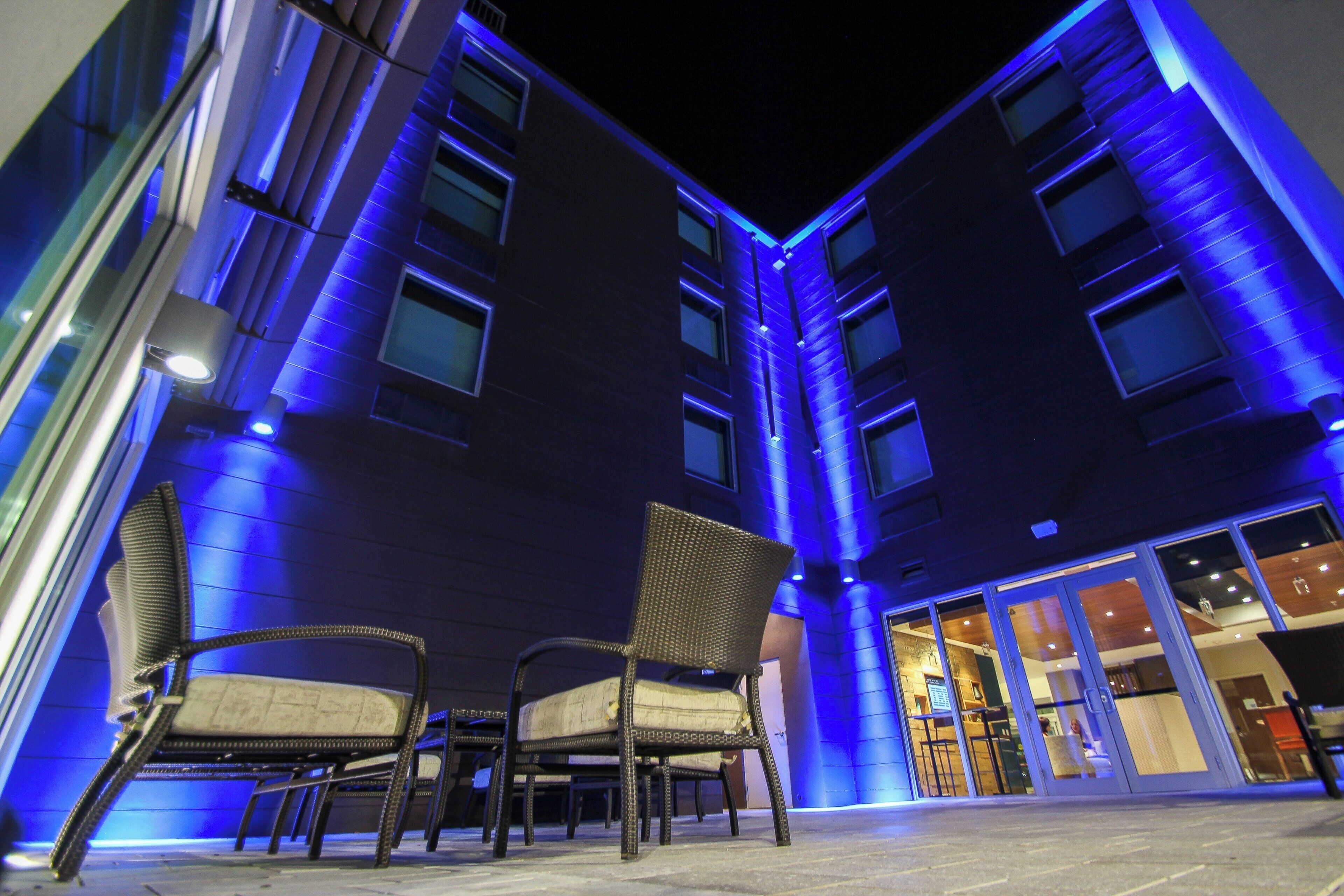 A building with multiple floors and a ground-level seating area with chairs.