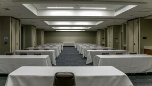 A conference room with rows of tables and chairs, equipped with nameplates and pens, and an exit sign on the wall.
