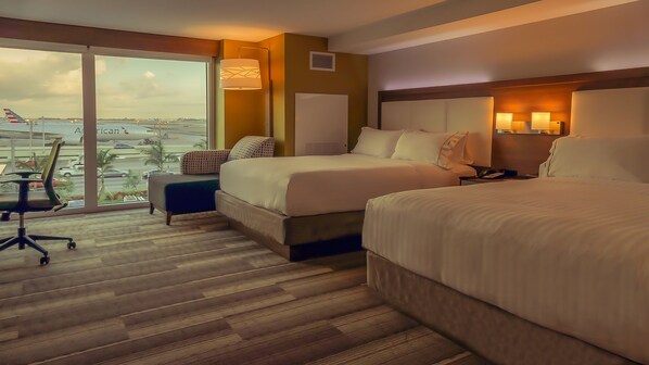 A hotel room with two beds, a desk, and a chair. There is a large window providing a view of the airport and cityscape. - Holiday Inn Express & Suites Miami Airport East by IHG (Miami)