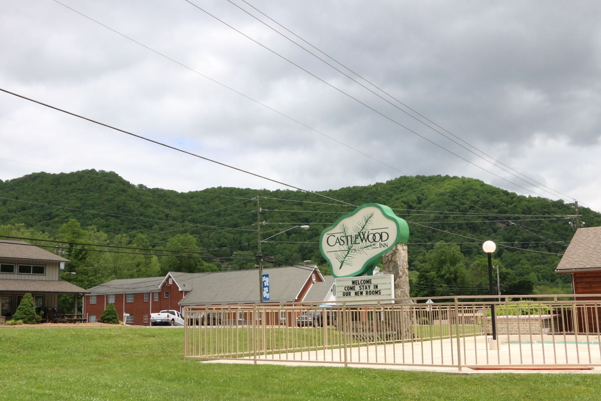 A Castlewood Inn sign with a welcoming message and a view of a green hill in the background.