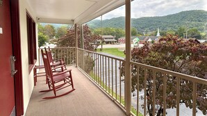 A balcony with a view of a green landscape and a church. - Castlewood Inn (Maggie Valley)