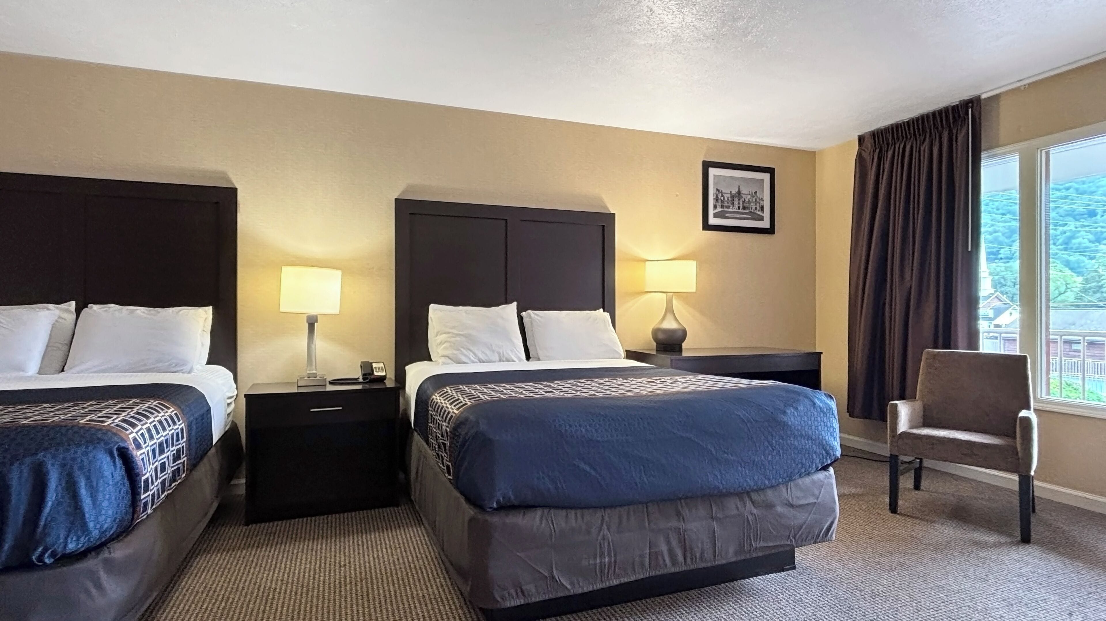 Une chambre d  ’hôtel avec deux lits, une chaise, une table de chevet avec une lampe et un tableau au mur.