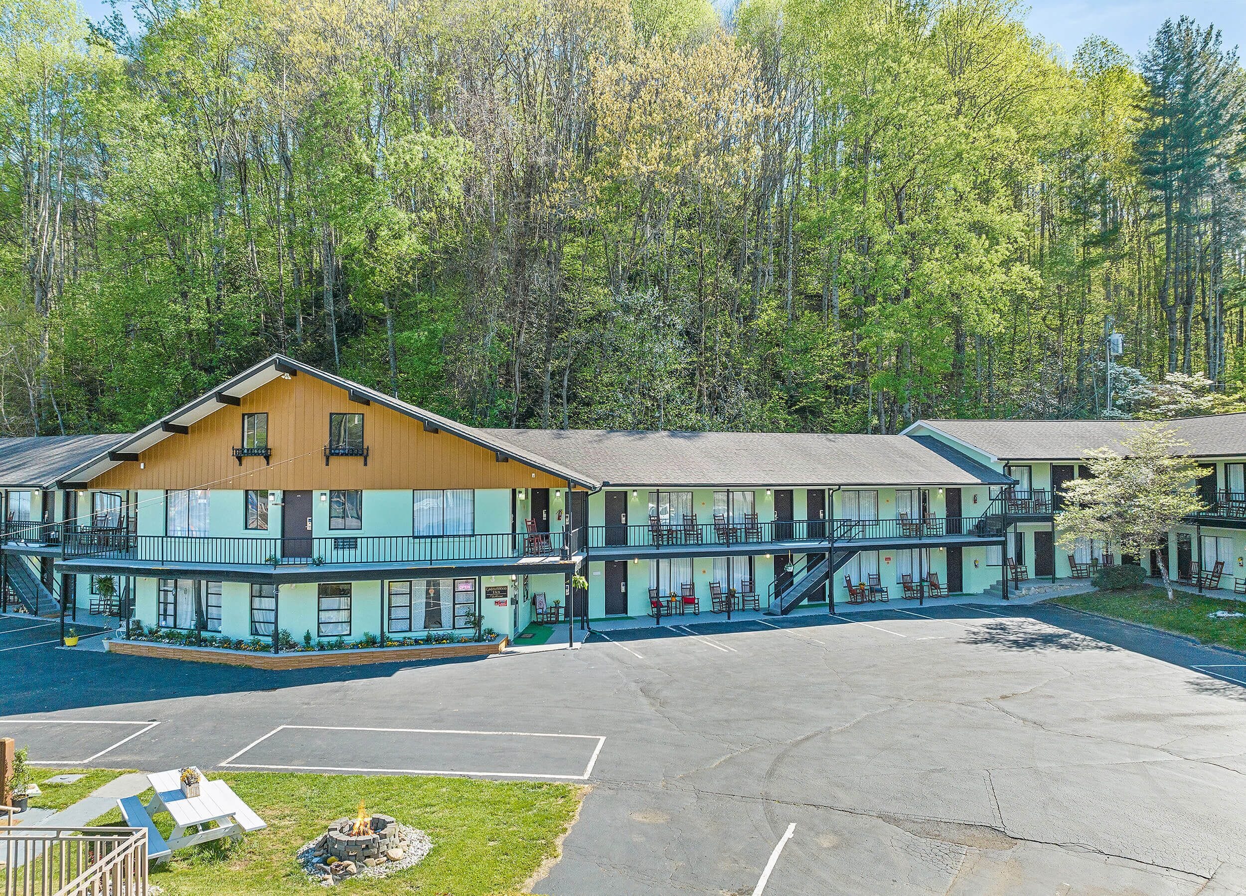 A motel with a two-story structure, outdoor seating, and a parking lot.