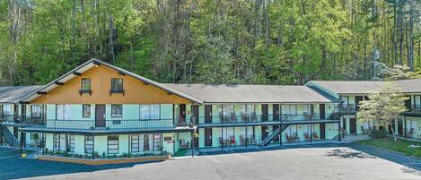 A motel with a two-story structure, outdoor seating, and a parking lot.