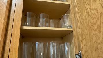 A wooden cabinet with multiple shelves containing clear glassware.