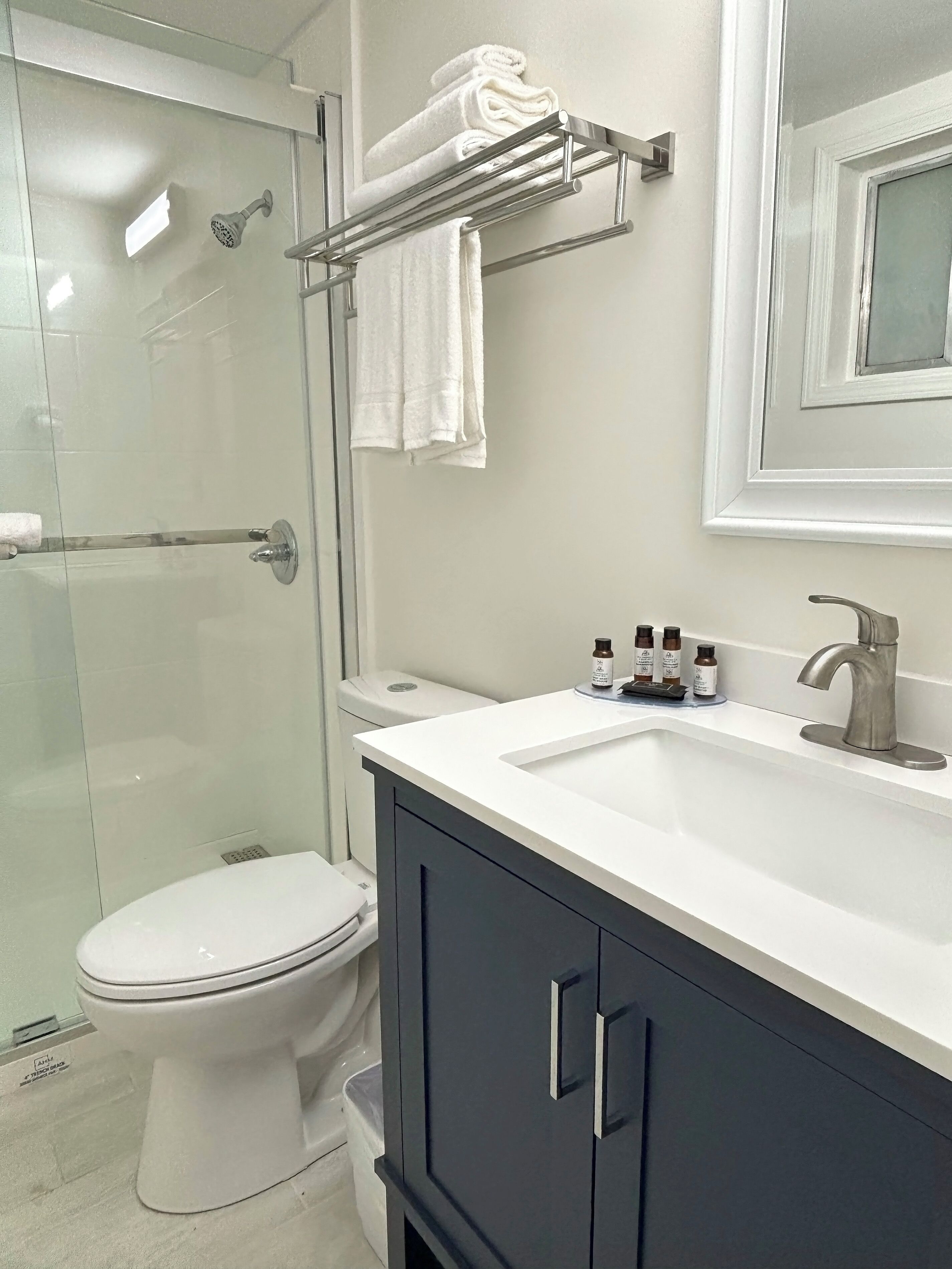 Un bagno moderno con cabina doccia in vetro, un water bianco, un mobile lavabo e un porta asciugamani.