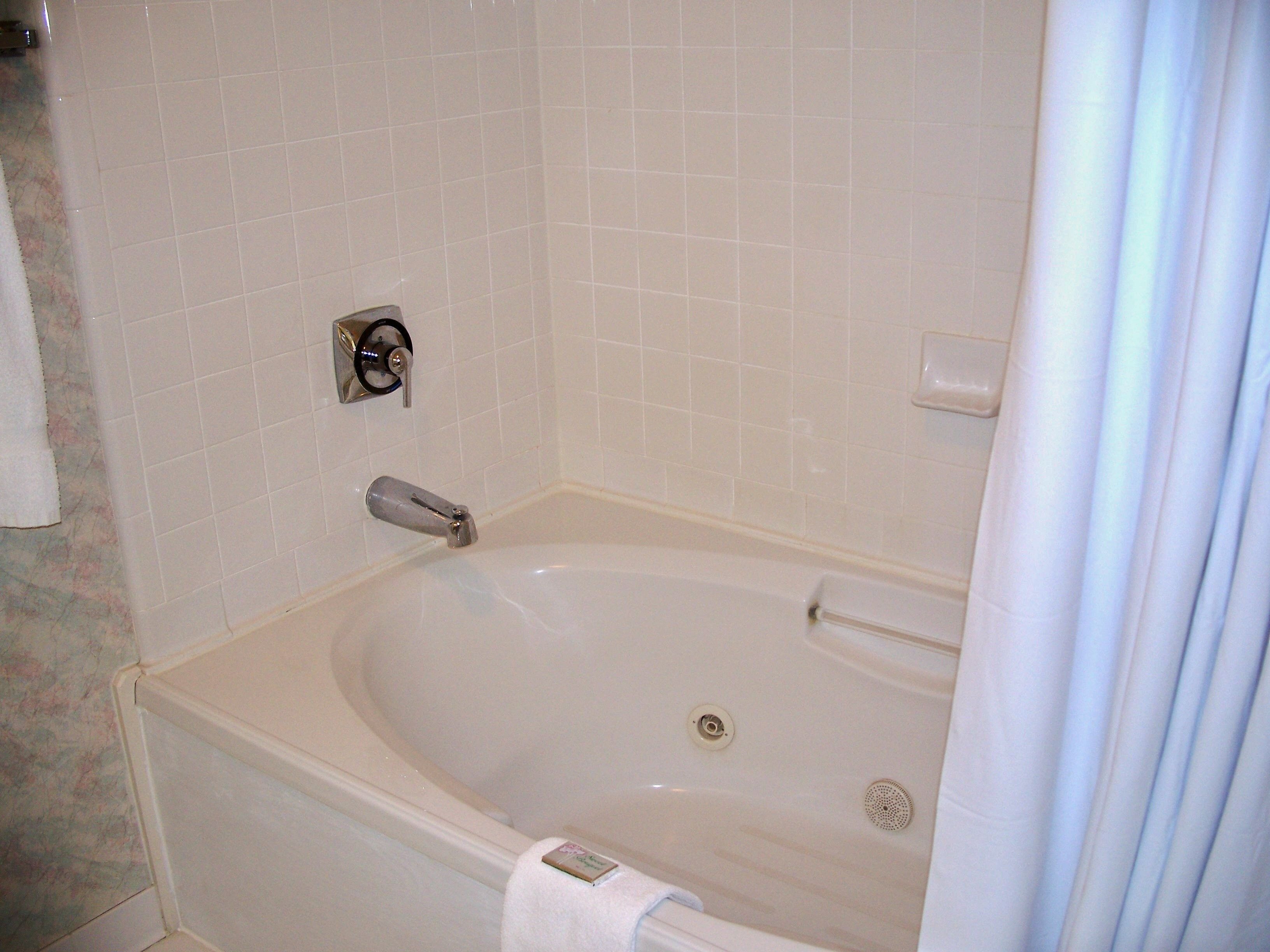 A white bathtub with a control panel and a shower curtain.