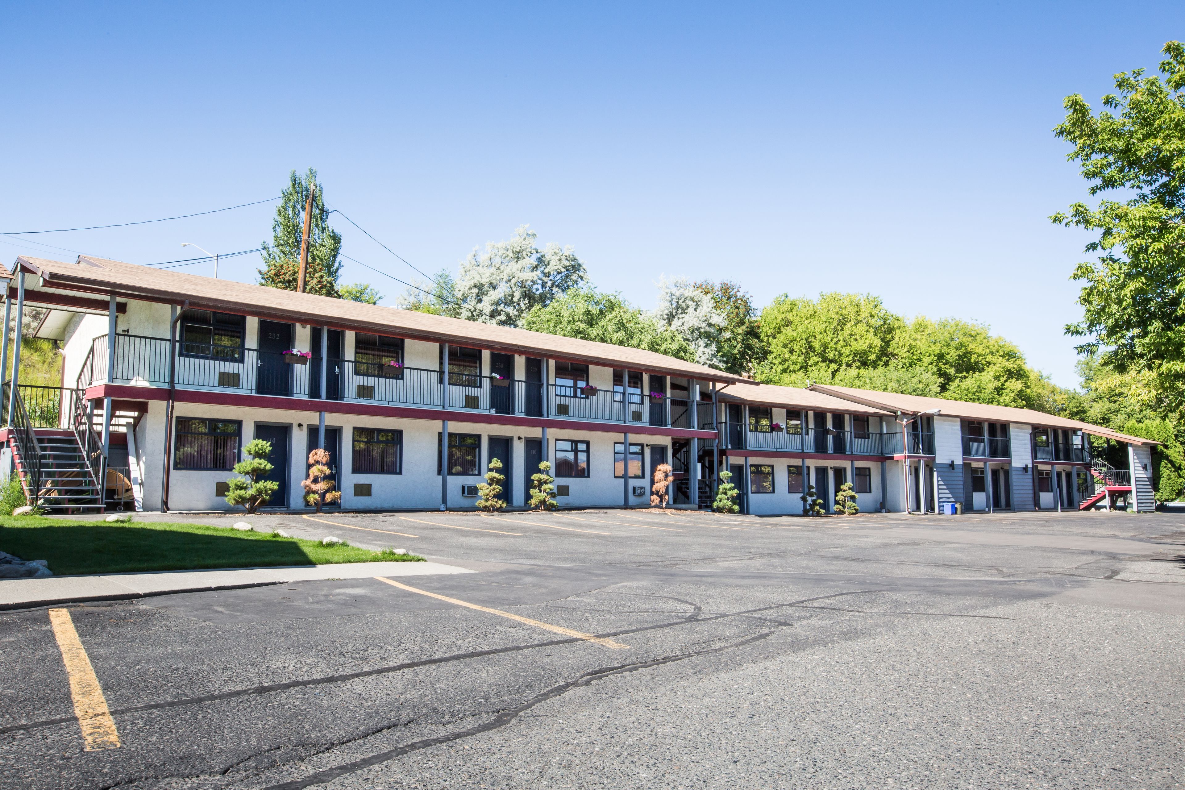 Ein Motel mit mehreren Etagen, einem Parkplatz und einer kleinen Grünfläche.