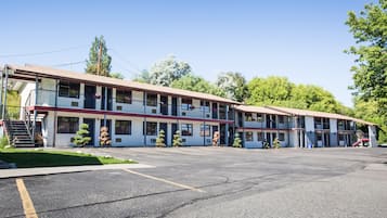 Ein Motel mit mehreren Etagen, einem Parkplatz und einer kleinen Grünfläche.