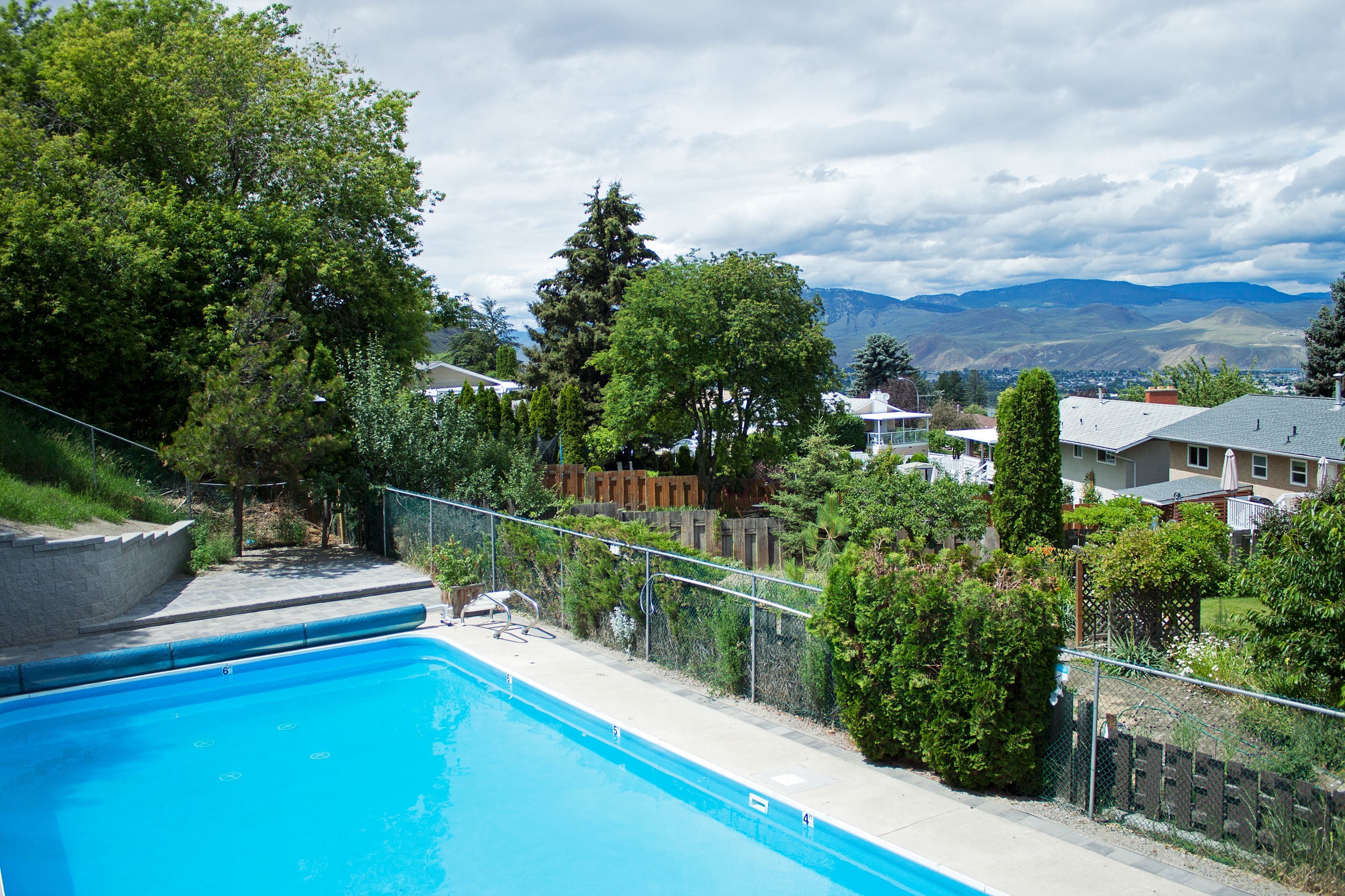 A swimming pool with a view of houses and mountains in the background.