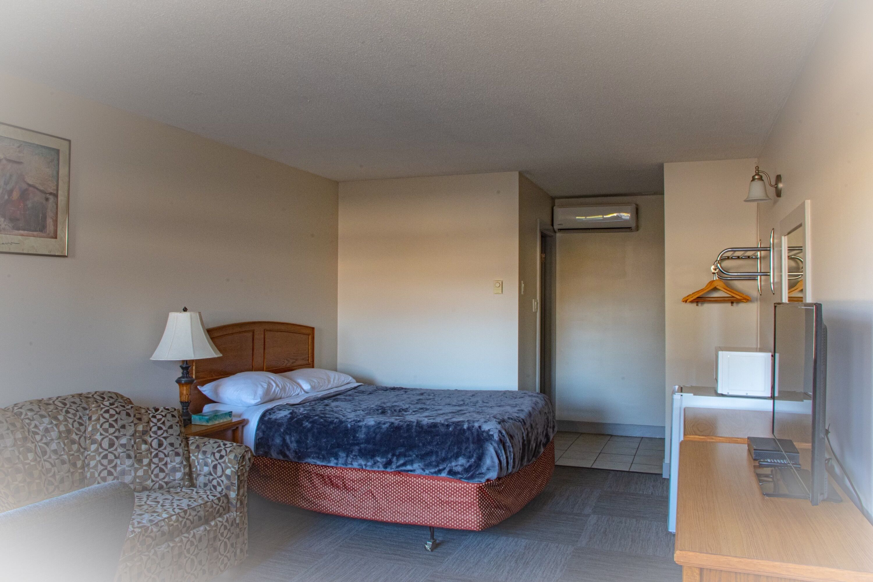 Une chambre d’hôtel équipée d’un lit, d’une chaise, d’un bureau, d’une télévision et d’un appareil de climatisation.