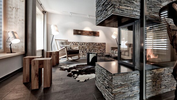 A modern interior with a stone wall, wooden furniture, and a glass partition. - Valbella Resort (Vaz-Obervaz)