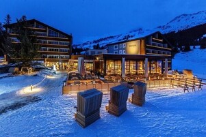 A hotel with a large outdoor seating area, multiple floors, and a mountain backdrop.