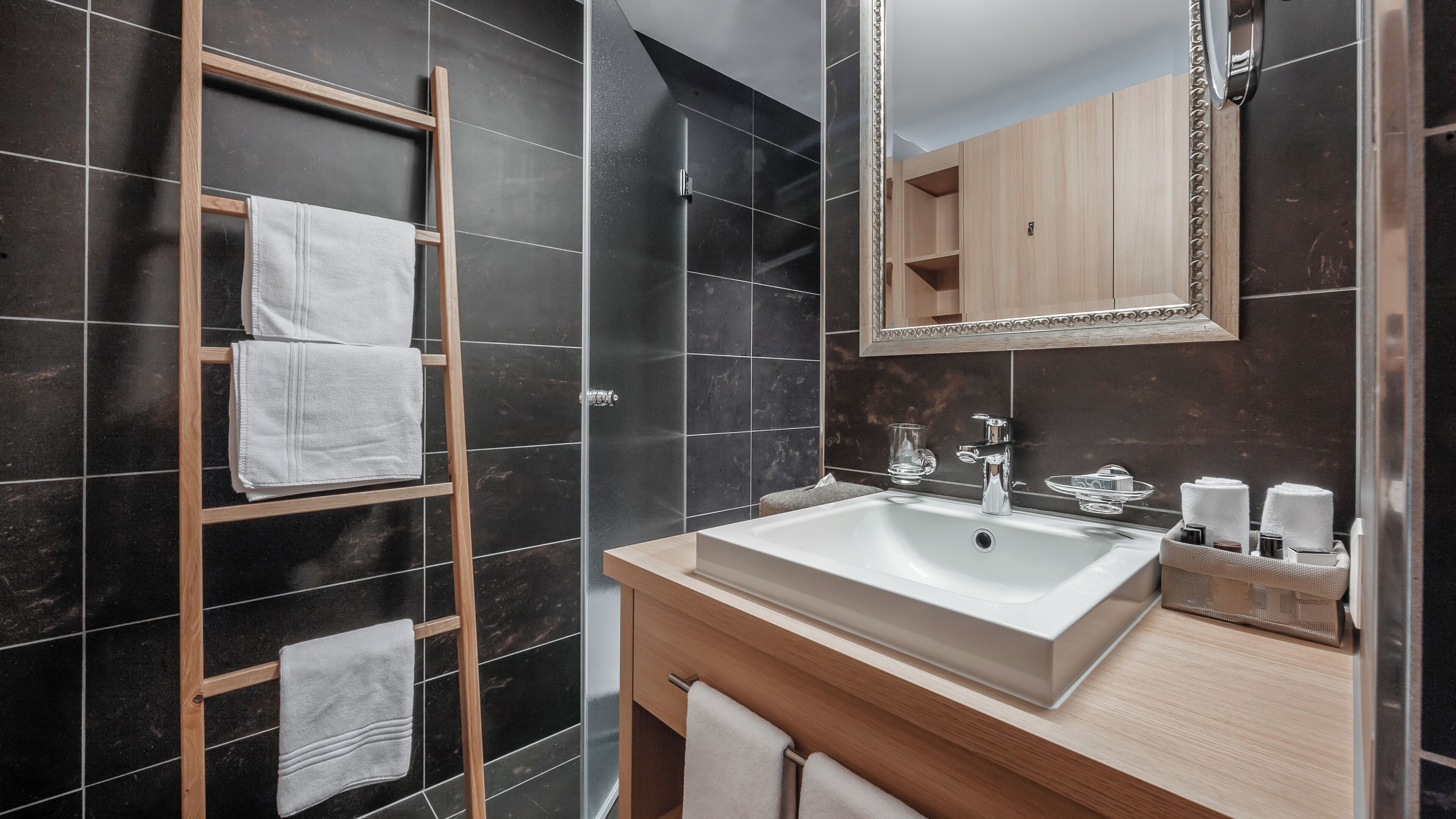 Ein modernes Badezimmer mit einem großen Waschbecken, einem Holzhandtuchhalter und einem Spiegel über dem Waschbecken.