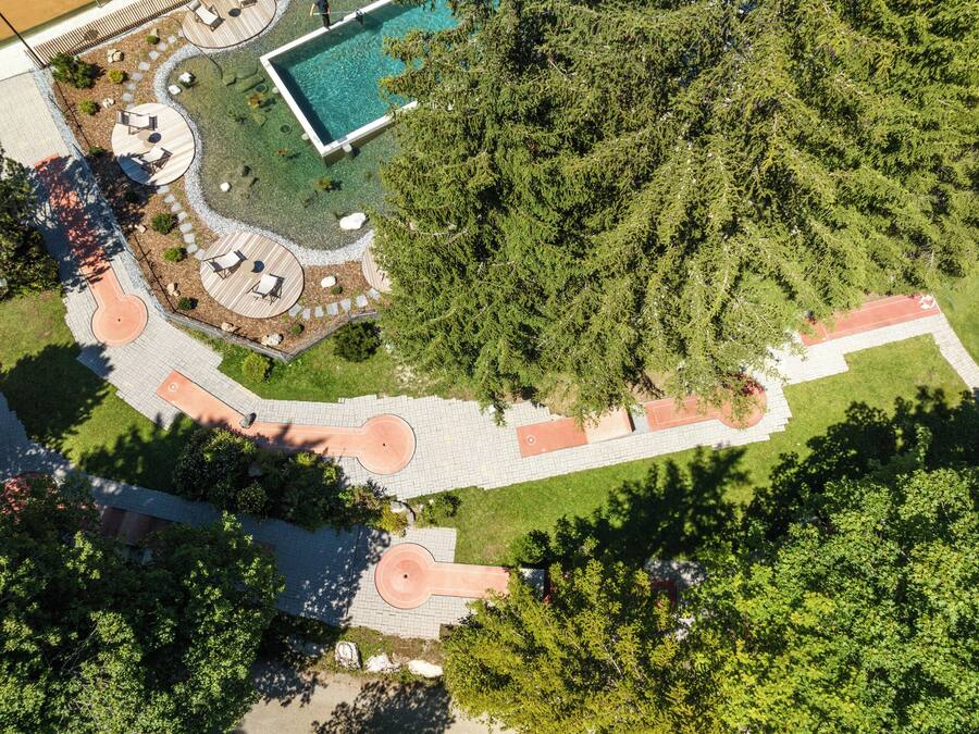 An aerial view of a park with a swimming pool, picnic areas, and a running track.