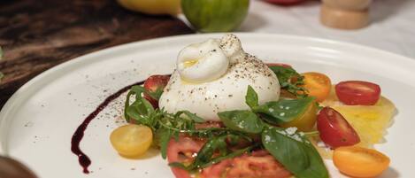 Prato com ovo pochê, tomates e folhas verdes.