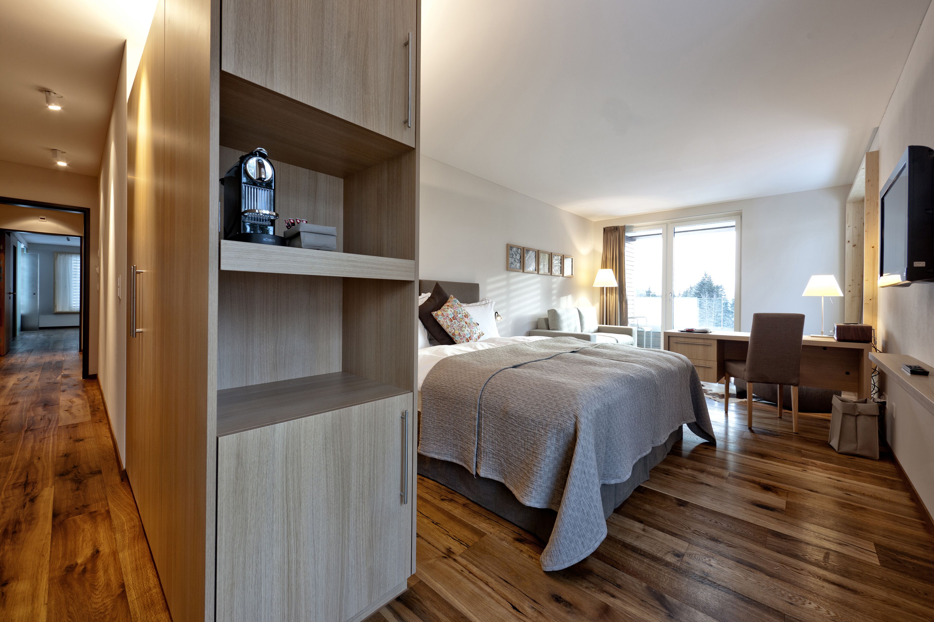 A modern hotel room with a large bed, a desk, and a television.