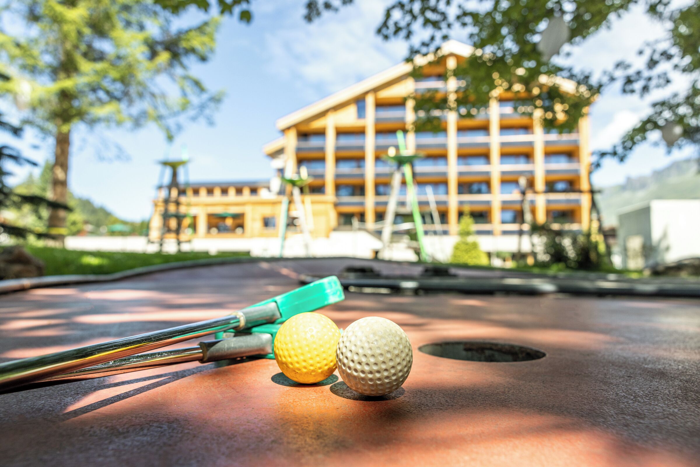 Pelotas y palos de golf sobre una mesa, con un edificio al fondo.