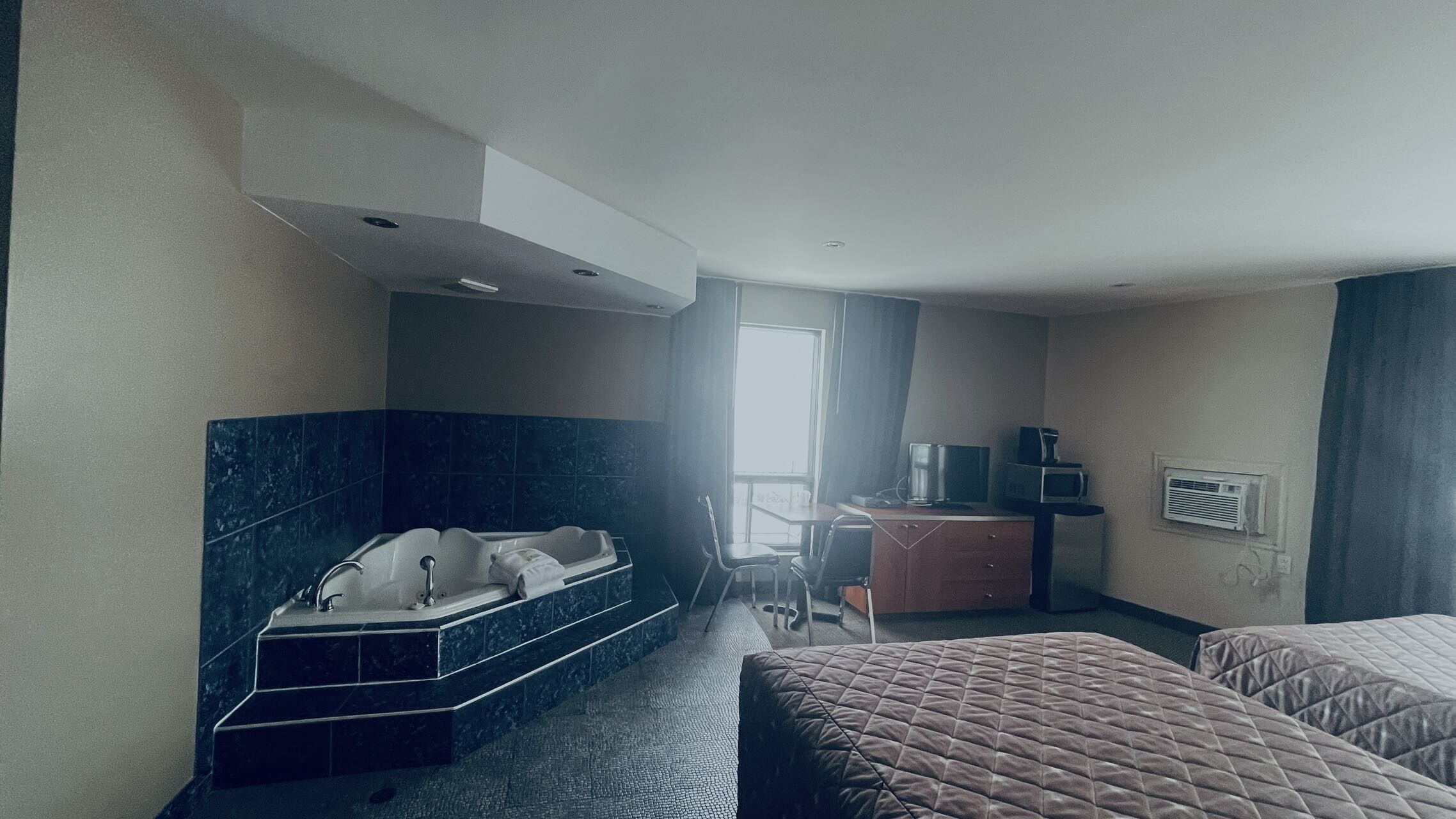 Habitació d'hotel amb banyera, escriptori, cadira i dos llits.