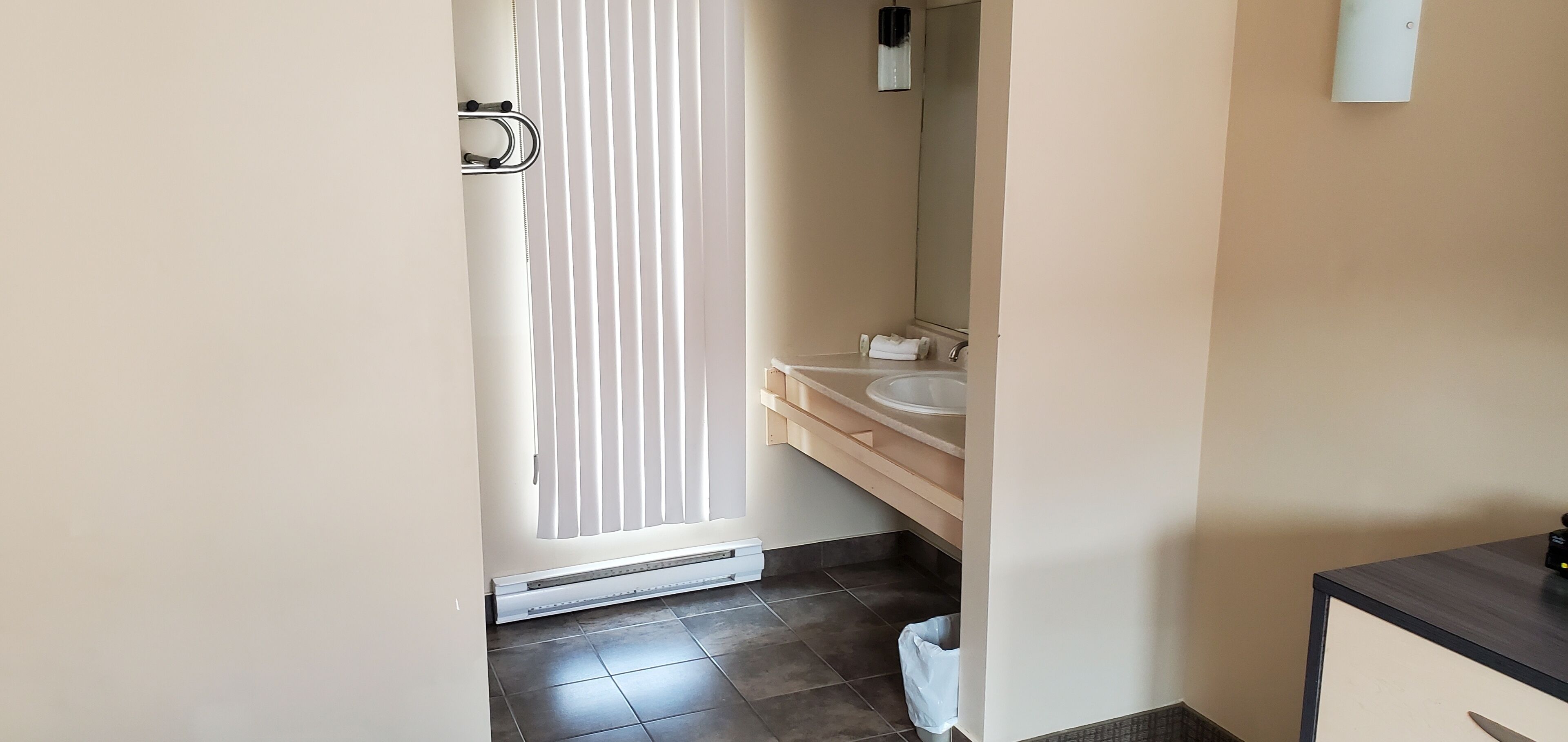 Un baño con inodoro, lavamanos, espejo y toallero.