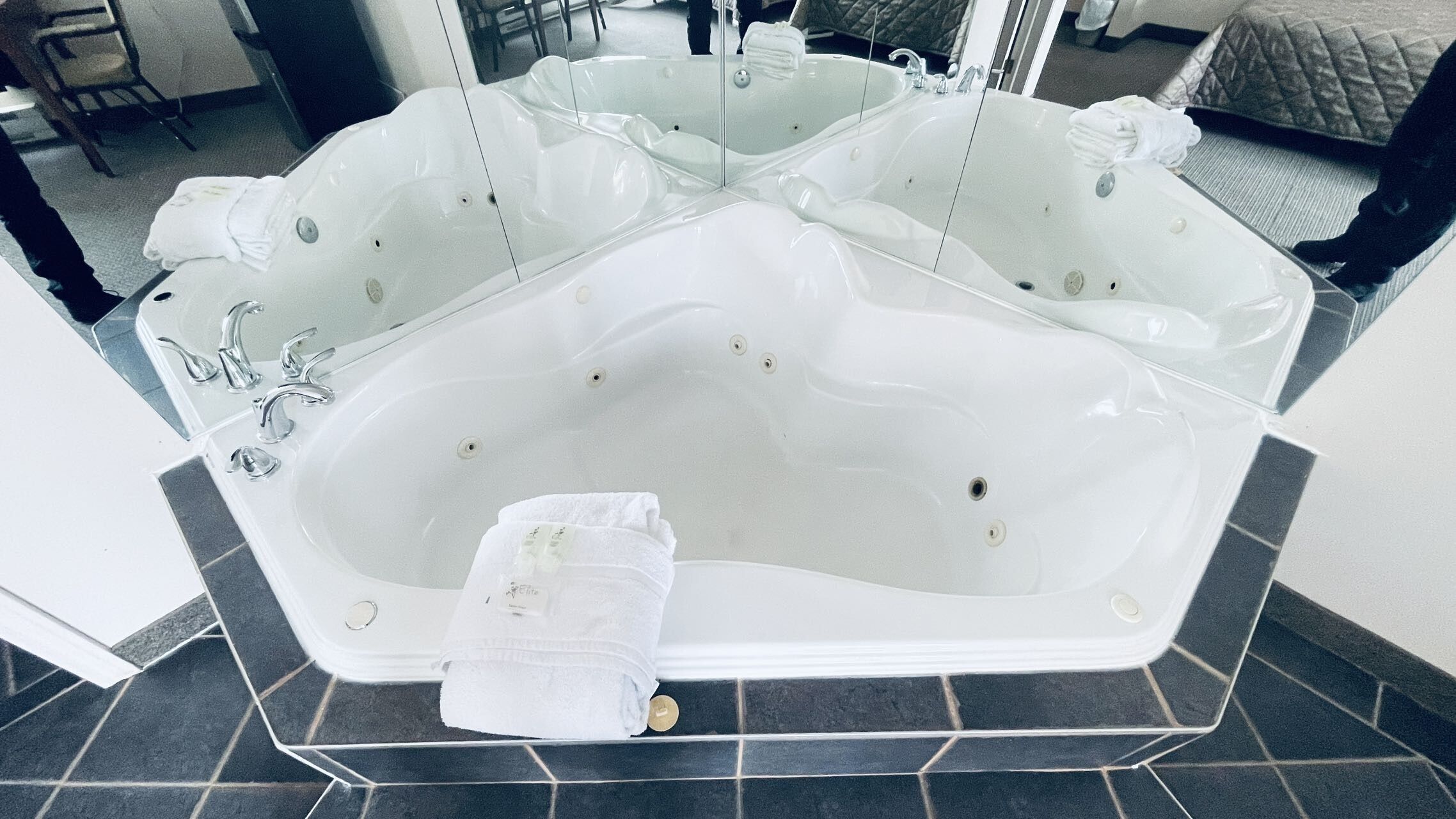 Una bañera blanca grande y separada, con varios grifos y una toalla a un lado.