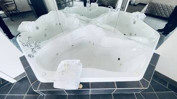 Una bañera blanca grande y separada, con varios grifos y una toalla a un lado.