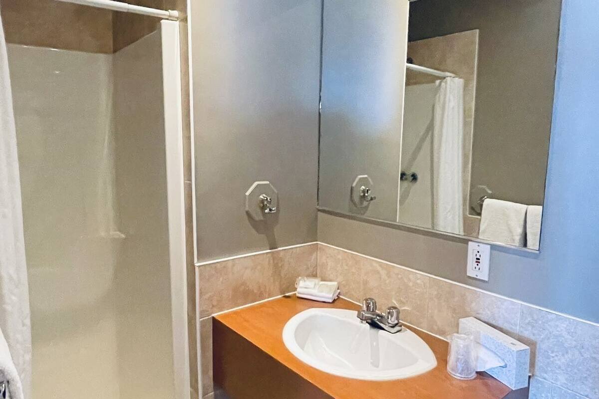 A modern bathroom with a walk-in shower, a sink with a mirror above it, and a towel rack.