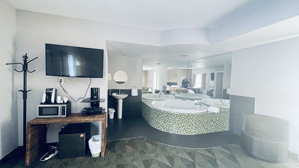 Een moderne hotelbadkamer met een grote spiegel, een badkuip en een aparte douchehoek.