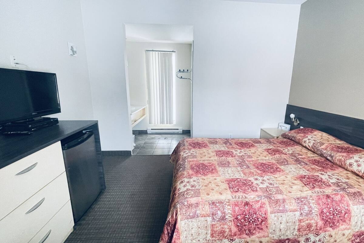 A hotel room with a bed, a TV, a desk, and a wardrobe.