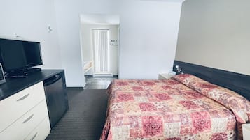 Ein Hotelzimmer mit Bett, Fernseher, Schreibtisch und Kleiderschrank.