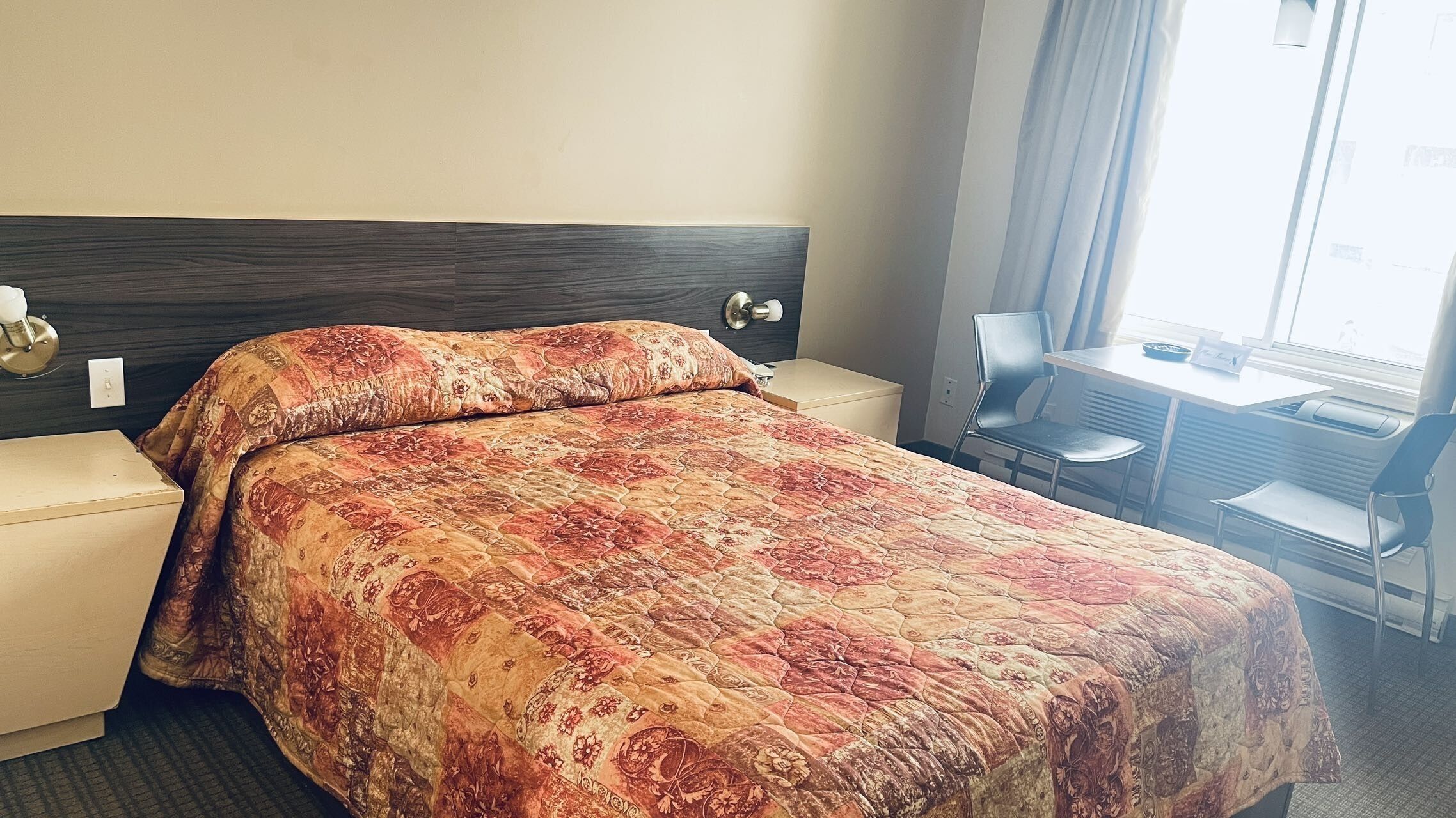 A hotel room with a bed, a desk, and a chair.