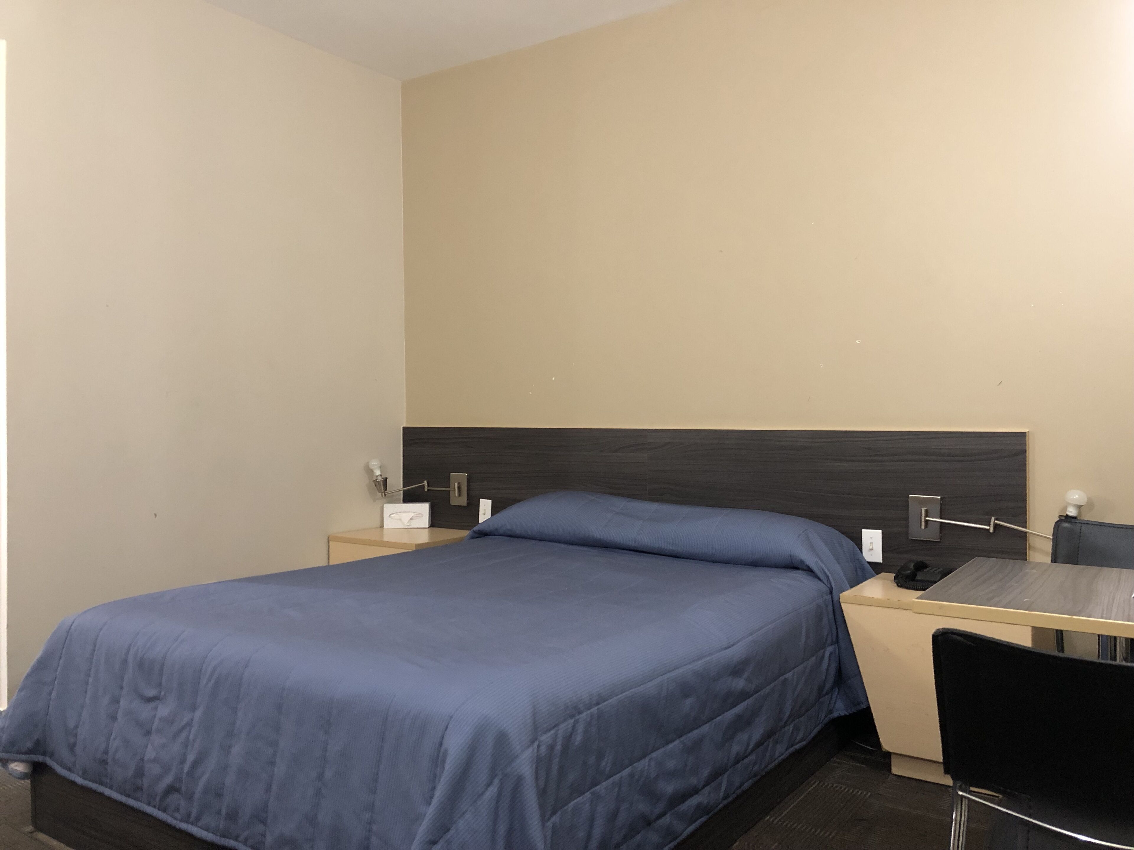 Habitació d'hotel amb llit, escriptori i cadira.
