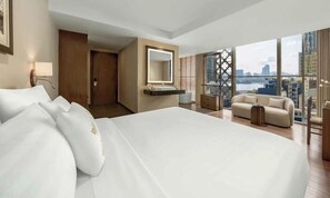 A modern hotel room with a large bed, a vanity with a mirror, a sofa, and a city view. - Silverland Sakyo Hotel & Spa (Ho Chi Minh City)