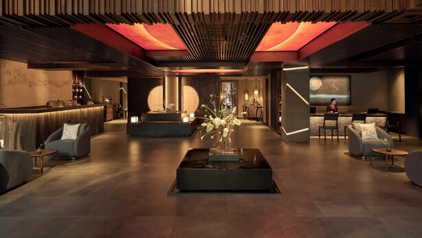 A modern lobby with a reception desk, seating areas, and a large screen displaying a scenic view. - Silverland Sakyo Hotel & Spa (Ho Chi Minh City)