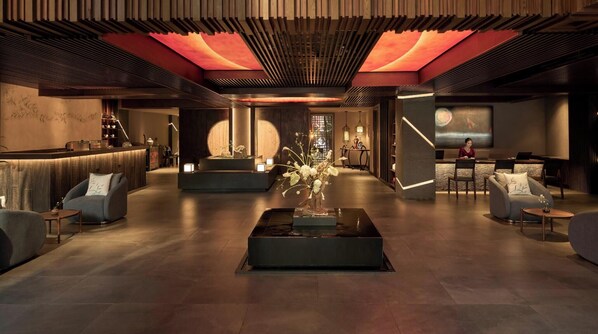 A modern lobby with a reception desk, seating areas, and a large screen displaying a scenic view. - Silverland Sakyo Hotel & Spa (Ho Chi Minh City)