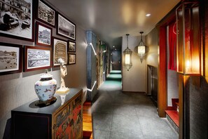 A hallway with framed photographs on the walls, a decorative vase on a console table, and a staircase with a red accent. - Silverland Sakyo Hotel & Spa (Ho Chi Minh City)