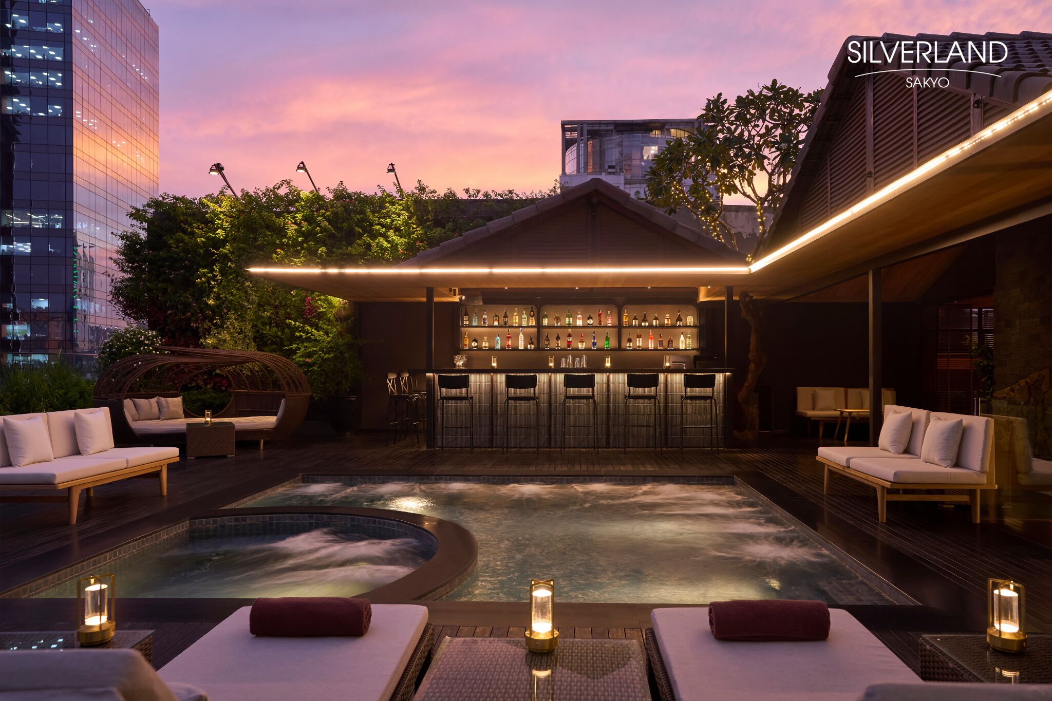 A rooftop bar with a pool, lounge chairs, and a bar stocked with bottles.