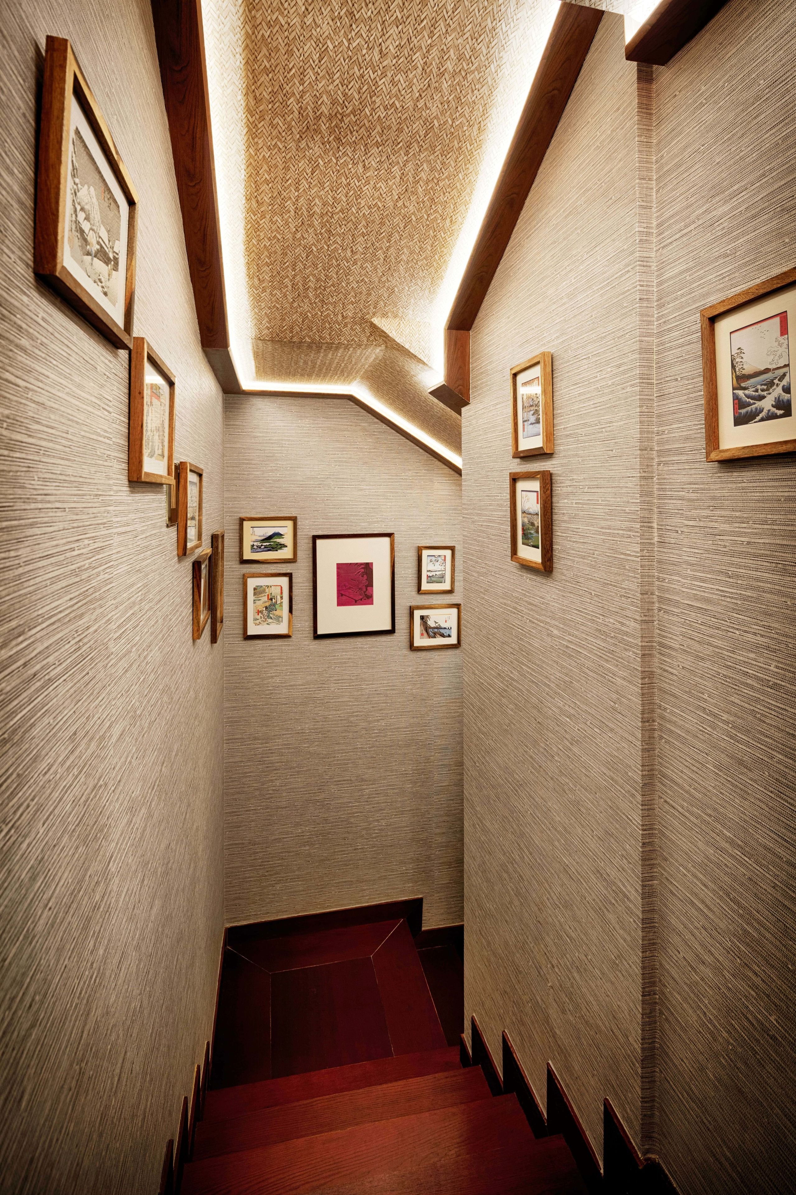 A narrow hallway with wooden walls and a red carpeted staircase.
