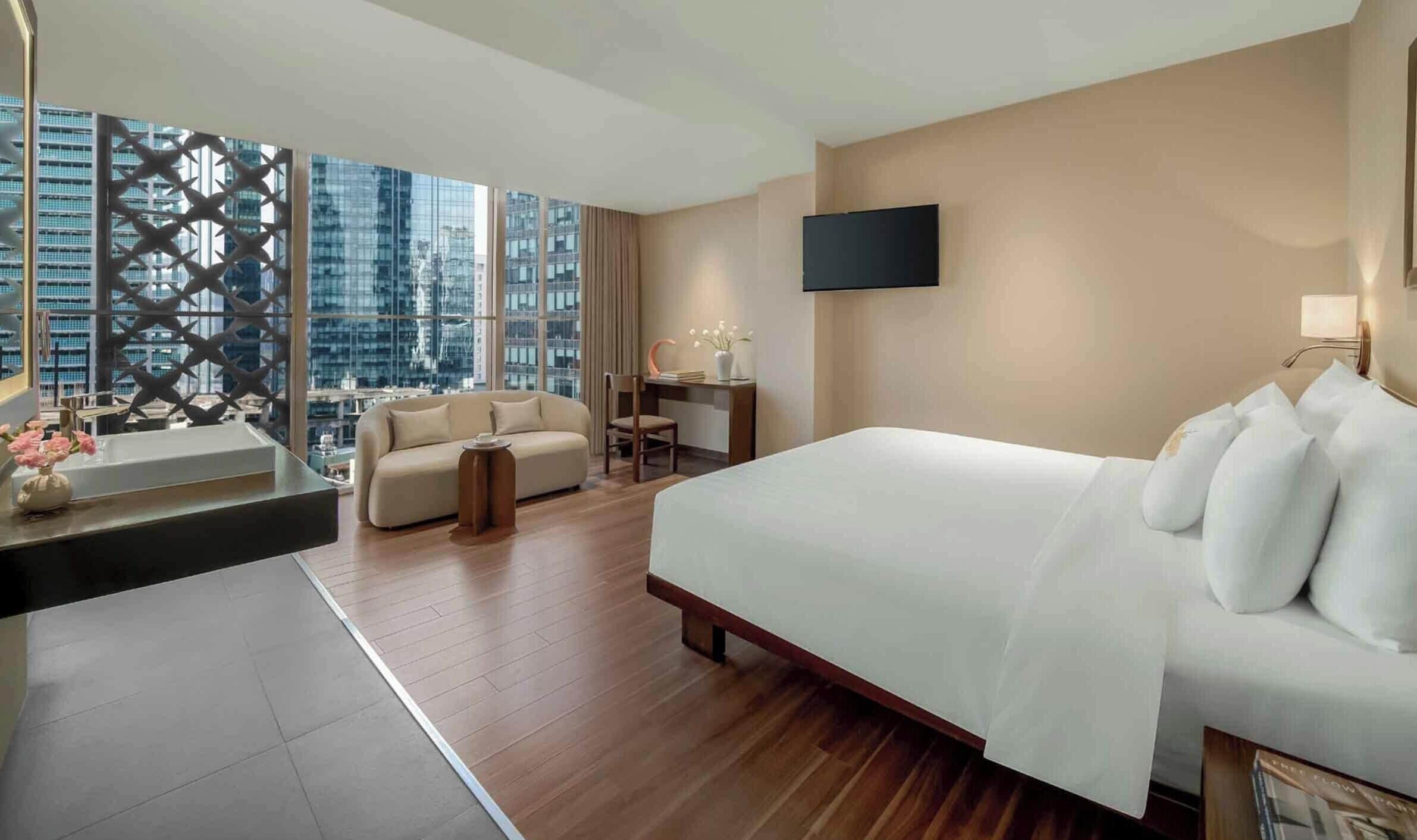 Una habitación de hotel con una cama grande, un sofá, un escritorio y un televisor.