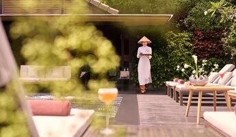 Una tranquilla zona relax all'aperto con una fontana, poltrone e una persona in abiti tradizionali.