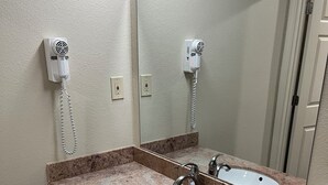 A bathroom with two sinks, a mirror, and a hairdryer on the wall. - Western Motel (Salinas)