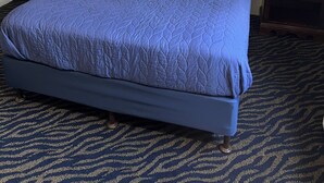 A hotel room with a large bed, a bedside phone, a framed picture on the wall, and a carpeted floor. - Western Motel (Salinas)
