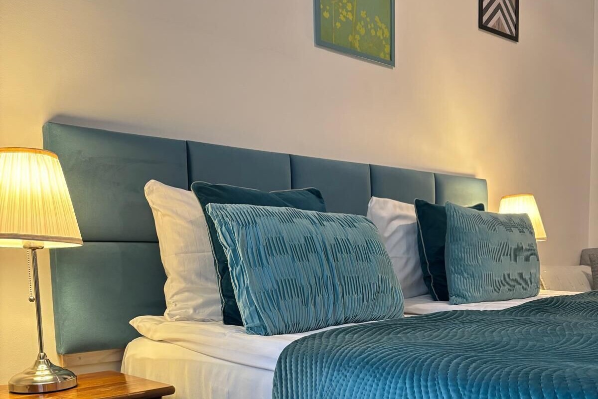 A bedroom with a bed, nightstands, and wall art.