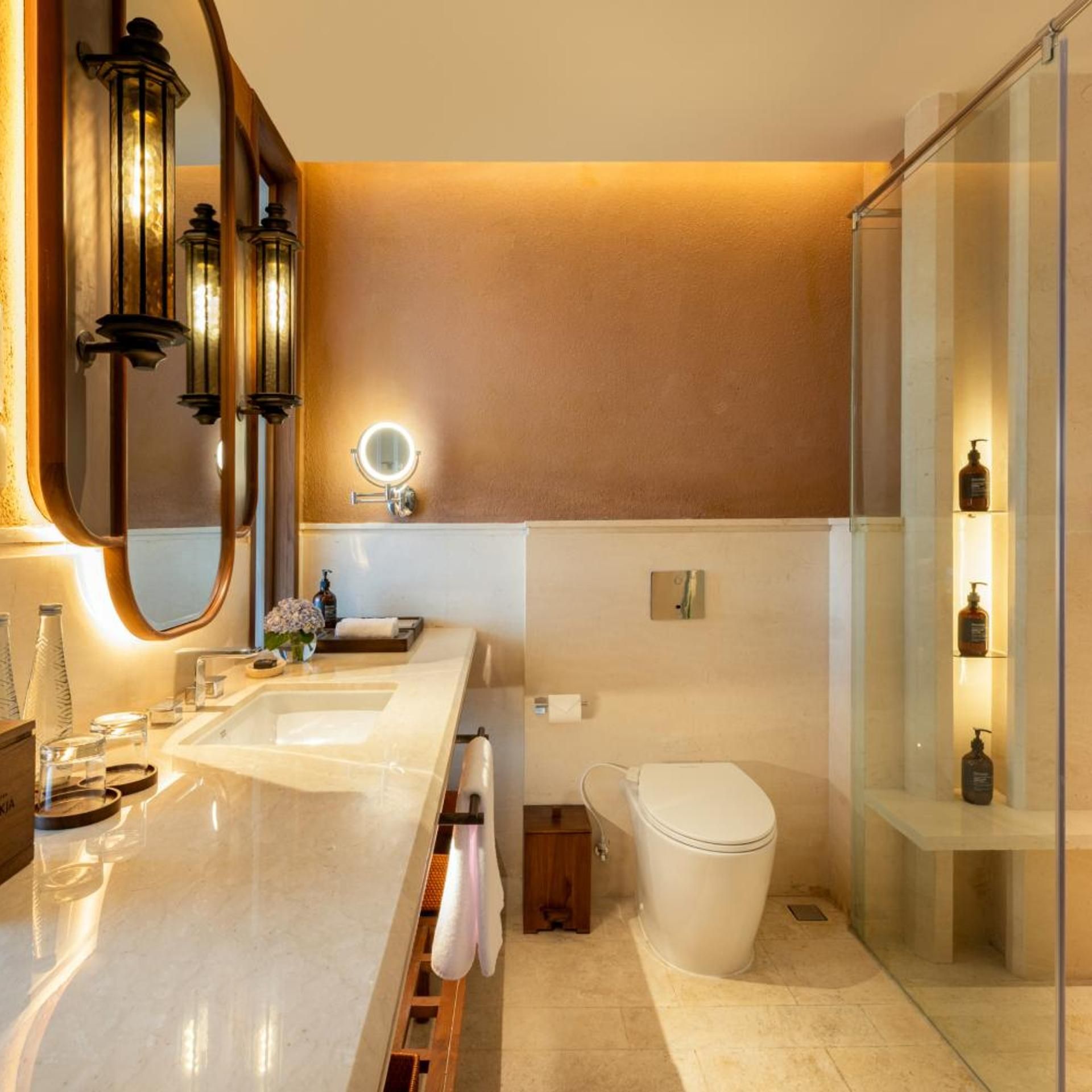 Une salle de bain moderne avec un grand miroir, un lavabo, des toilettes et une douche à parois de verre.