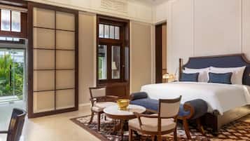 Une chambre d’hôtel avec un grand lit, un ventilateur de plafond, une table à manger avec des chaises et une vue accessible par une porte coulissante.