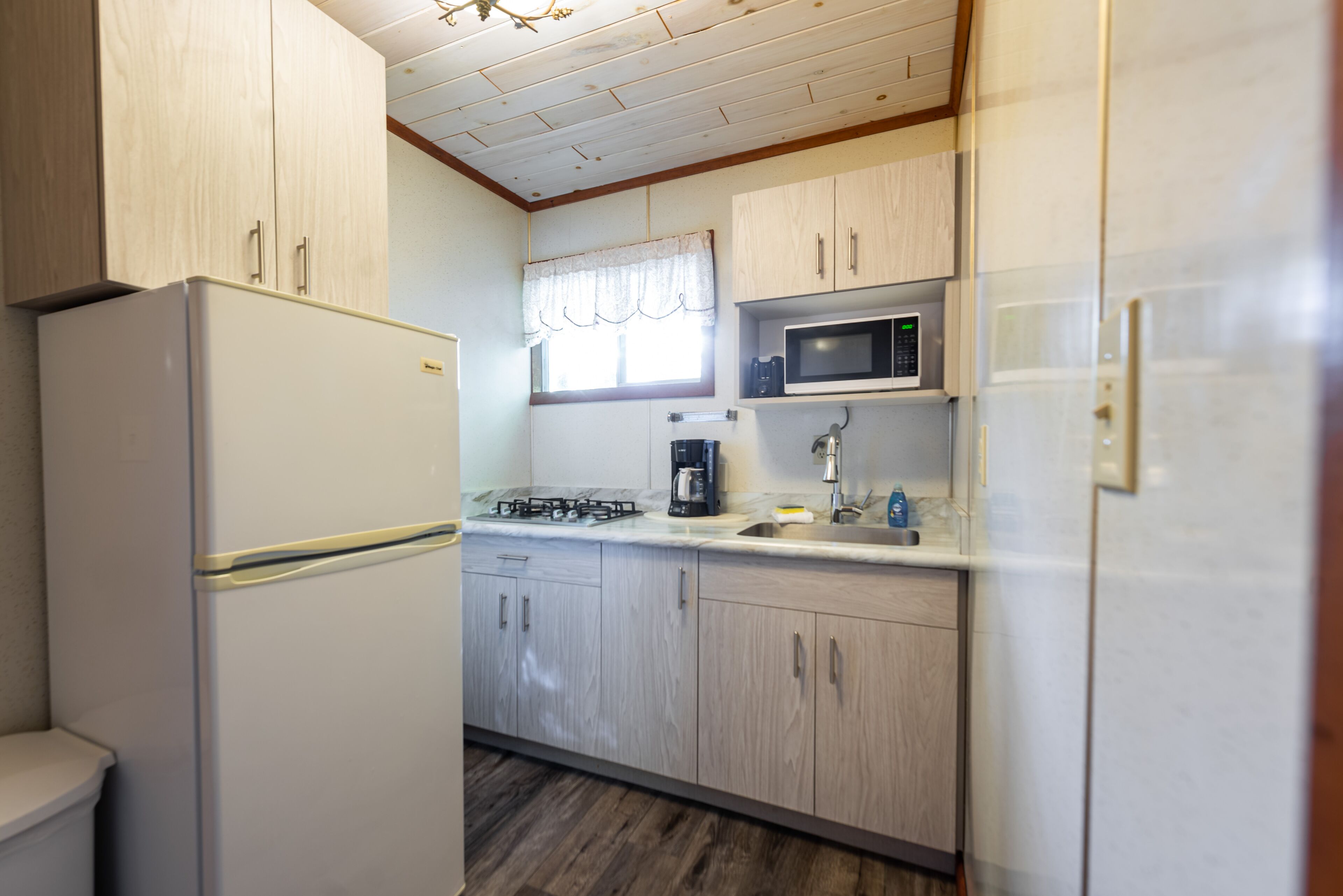 A compact kitchen with a refrigerator, microwave, stove, and cabinets.